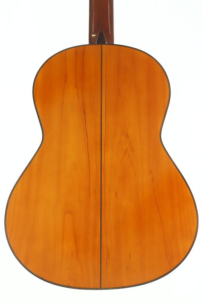 Die Rückseite der Flamenco-Gitarre „Casa Arcangel Fernandez 1970“ weist eine polierte, hellbraune Holzoberfläche mit einer deutlich sichtbaren dunklen Mittelnaht auf; das Foto zeigt das Instrument vor weißem Hintergrund. Die Rückseite der Flamenco-Gitarre „Casa Arcangel Fernandez 1970“ weist eine polierte, hellbraune Holzoberfläche mit einer deutlich sichtbaren dunklen Mittelnaht auf; das Foto zeigt das Instrument vor weißem Hintergrund.