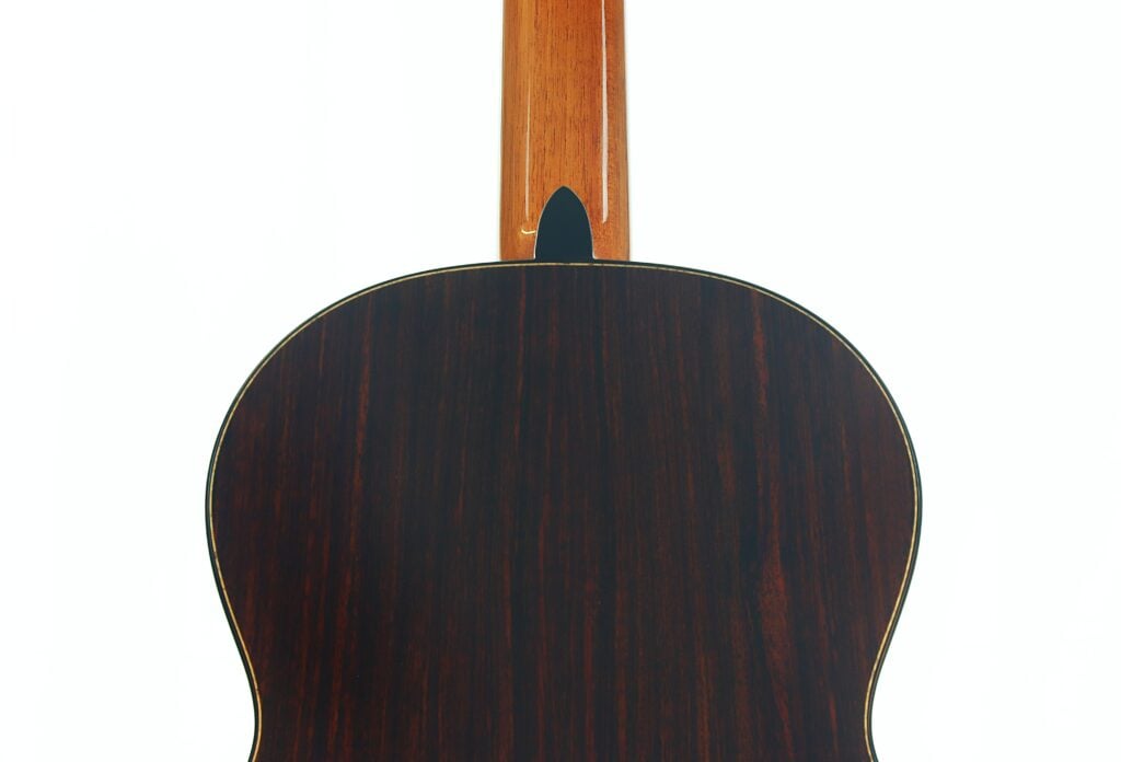 Rückansicht der Lester DeVoe 2020 Negra Flamenco-Gitarre, die ihren Korpus und Hals mit dunkler Holzmaserung vor einem schlichten weißen Hintergrund zur Geltung bringt. Rückansicht der Lester DeVoe 2020 Negra Flamenco-Gitarre, die ihren Korpus und Hals mit dunkler Holzmaserung vor einem schlichten weißen Hintergrund zur Geltung bringt.