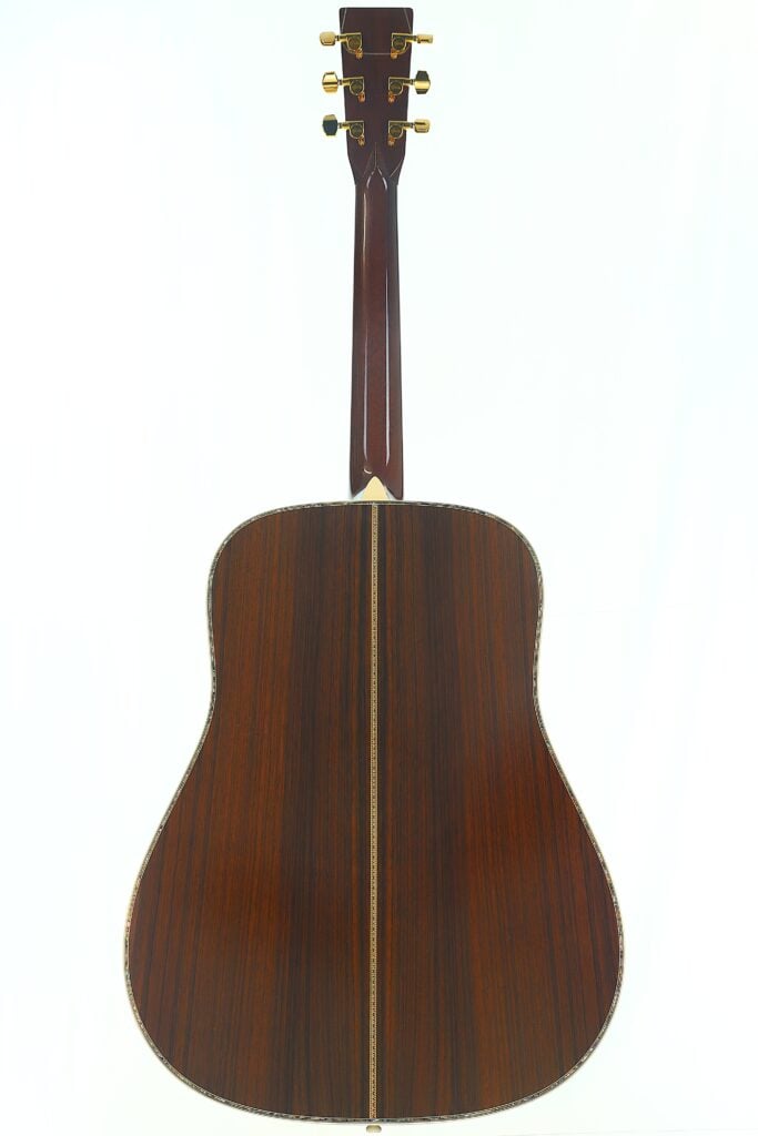 Der Boden einer Akustikgitarre mit dunkler Holzoberfläche, goldenen Stimmwirbeln und einer dekorativen Einlage, die in der Mitte des Korpus verläuft. Der Boden einer Akustikgitarre mit dunkler Holzoberfläche, goldenen Stimmwirbeln und einer dekorativen Einlage, die in der Mitte des Korpus verläuft.