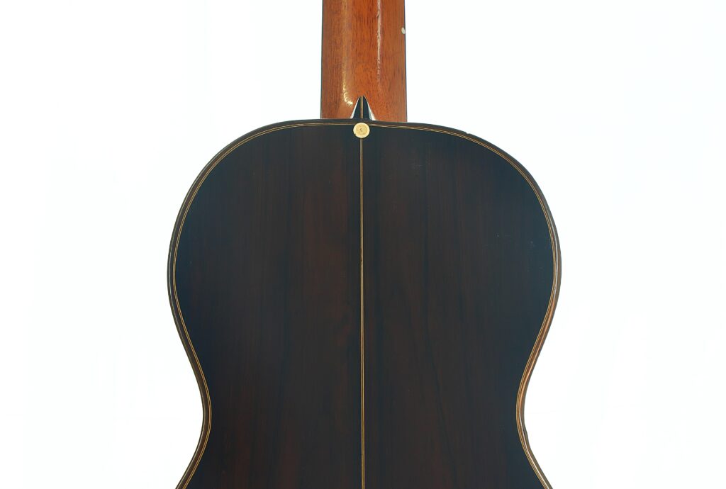 Die Rückseite der „Romantikgitarre“ von Louis Panormo aus dem Jahr 1827 ist mit einer dunklen Holzoberfläche, hellen Kanten und einem Zierknopf oben in der Mitte versehen. Die Rückseite der „Romantikgitarre“ von Louis Panormo aus dem Jahr 1827 ist mit einer dunklen Holzoberfläche, hellen Kanten und einem Zierknopf oben in der Mitte versehen.