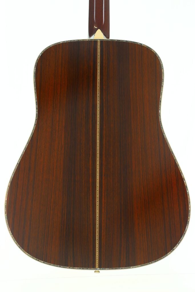 Die Rückseite einer Martin D-45 Akustikgitarre aus dem Jahr 2009, aus poliertem dunklem Holz mit einem vertikalen Einlegeband in der Mitte und Zierkanten, vor einem weißen Hintergrund. Die Rückseite einer Martin D-45 Akustikgitarre aus dem Jahr 2009, aus poliertem dunklem Holz mit einem vertikalen Einlegeband in der Mitte und Zierkanten, vor einem weißen Hintergrund.