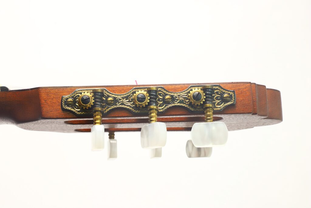Hier ist der überarbeitete Satz unter Verwendung der angegebenen Produktdaten: Nahaufnahme der Kopfplatte der „Tosca Klassische Gitarre“ von Frank-Peter Dietrich aus dem Jahr 1998, mit verzierten Stimmwirbeln aus Messing und weißen Drehknöpfen, vor einem schlichten weißen Hintergrund. Hier ist der überarbeitete Satz unter Verwendung der angegebenen Produktdaten: Nahaufnahme der Kopfplatte der „Tosca Klassische Gitarre“ von Frank-Peter Dietrich aus dem Jahr 1998, mit verzierten Stimmwirbeln aus Messing und weißen Drehknöpfen, vor einem schlichten weißen Hintergrund.