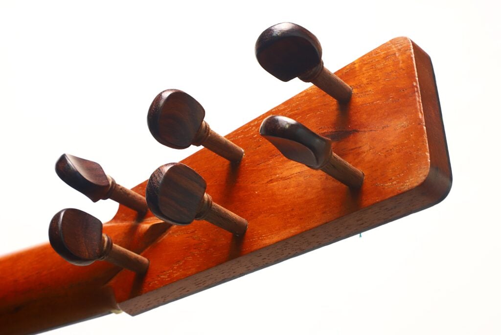 Nahaufnahme der hölzernen Stimmwirbel am Kopf der „Antonio Garcia de Lorca 1847 Replika Klassische Gitarre“ vor weißem Hintergrund. Nahaufnahme der hölzernen Stimmwirbel am Kopf der „Antonio Garcia de Lorca 1847 Replika Klassische Gitarre“ vor weißem Hintergrund.