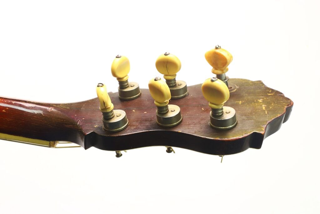 Die Rückseite des Kopfes einer Epiphone Recording B 1931 Akustikgitarre mit sechs gelben Stimmwirbeln vor einem schlichten weißen Hintergrund. Die Rückseite des Kopfes einer Epiphone Recording B 1931 Akustikgitarre mit sechs gelben Stimmwirbeln vor einem schlichten weißen Hintergrund.