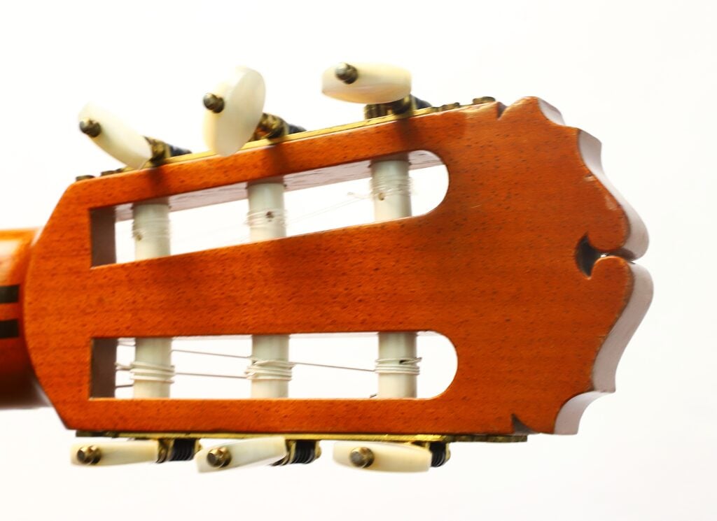 Nahaufnahme des Kopfes einer klassischen Gitarre vom Typ „Masaru Kohno Modell 50, Baujahr 1979“ mit weißen Stimmwirbeln und Nylonsaiten vor weißem Hintergrund. Nahaufnahme des Kopfes einer klassischen Gitarre vom Typ „Masaru Kohno Modell 50, Baujahr 1979“ mit weißen Stimmwirbeln und Nylonsaiten vor weißem Hintergrund.