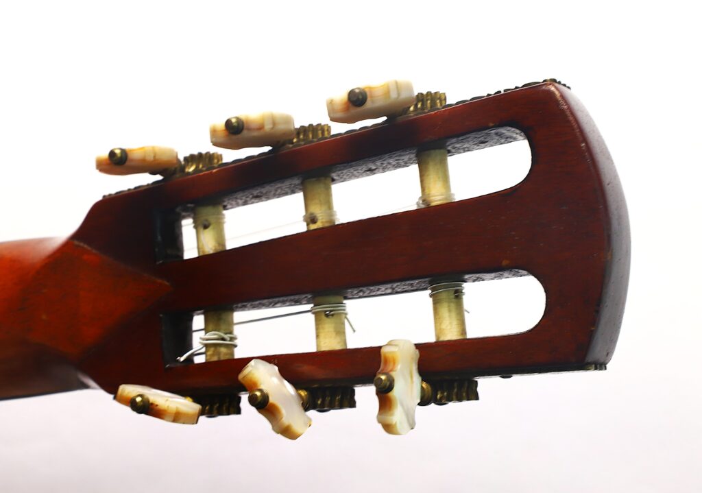 Nahaufnahme des Kopfstücks einer „Romantikgitarre“ von Louis Panormo aus dem Jahr 1827, bei der die hölzernen Stimmwirbel und die Metallsaiten vor einem weißen Hintergrund besonders hervorgehoben sind. Nahaufnahme des Kopfstücks einer „Romantikgitarre“ von Louis Panormo aus dem Jahr 1827, bei der die hölzernen Stimmwirbel und die Metallsaiten vor einem weißen Hintergrund besonders hervorgehoben sind.