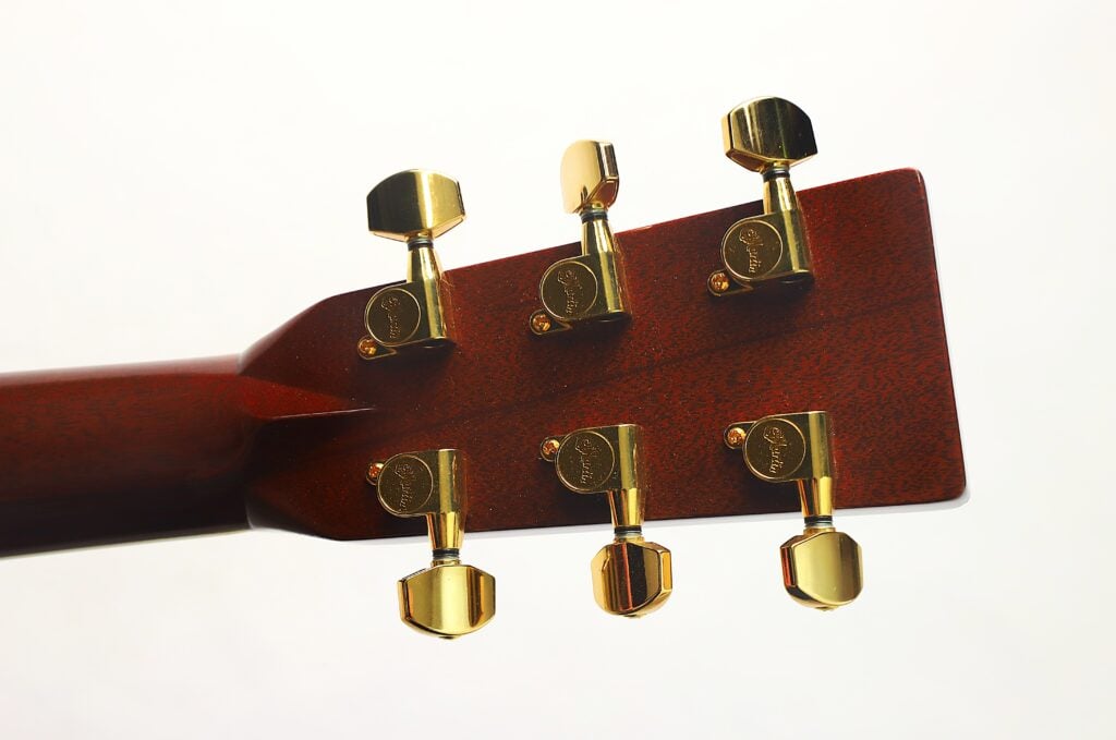 Nahaufnahme der Rückseite des Kopfes einer Martin D-45 Akustikgitarre aus dem Jahr 2009, auf der sechs goldene Stimmwirbel und ein Holzhals vor weißem Hintergrund zu sehen sind. Nahaufnahme der Rückseite des Kopfes einer Martin D-45 Akustikgitarre aus dem Jahr 2009, auf der sechs goldene Stimmwirbel und ein Holzhals vor weißem Hintergrund zu sehen sind.