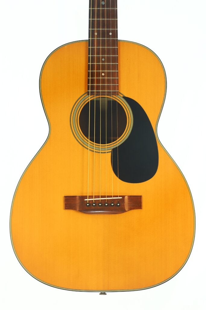 Martin 00-21 1986 Akustikgitarre mit hellem Holzkorpus, dunklem Schlagbrett und sechs Saiten, fotografiert vor weißem Hintergrund. Martin 00-21 1986 Akustikgitarre mit hellem Holzkorpus, dunklem Schlagbrett und sechs Saiten, fotografiert vor weißem Hintergrund.