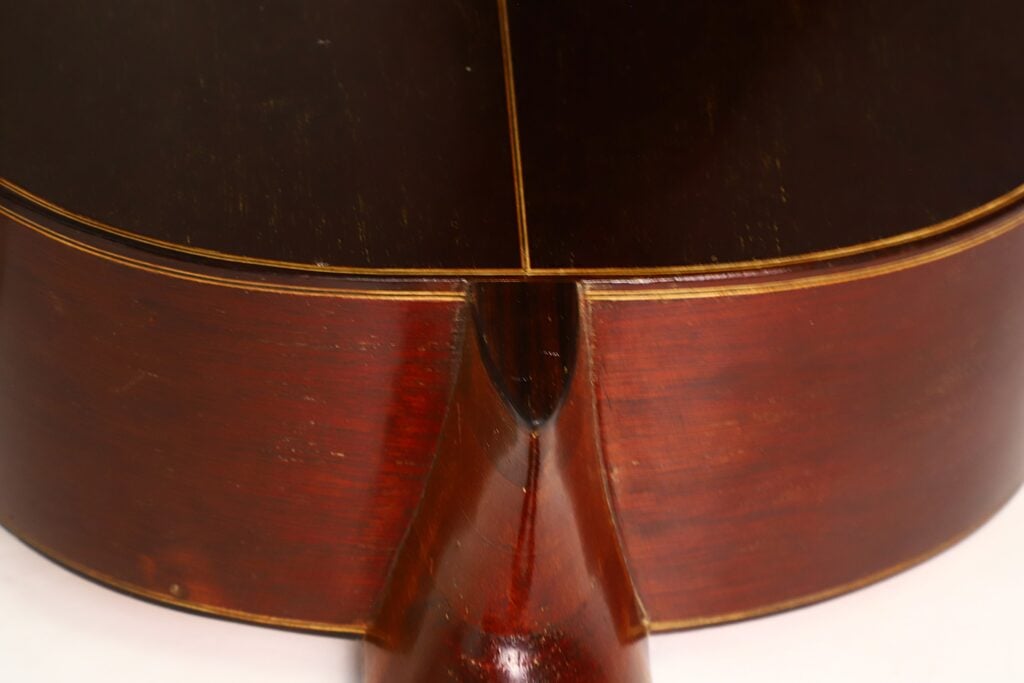 Nahaufnahme des Hals-Korpus-Übergangs der „Klassische Gitarre“ von Andres Martin aus dem Jahr 1966, die das rotbraune, polierte Holz und die außergewöhnliche Handwerkskunst besonders gut zur Geltung bringt. Nahaufnahme des Hals-Korpus-Übergangs der „Klassische Gitarre“ von Andres Martin aus dem Jahr 1966, die das rotbraune, polierte Holz und die außergewöhnliche Handwerkskunst besonders gut zur Geltung bringt.
