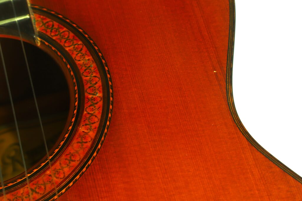 Nahaufnahme des Schalllochs und des Korpus der „Ramirez 1a 1985 Klassische Gitarre“, die die Holzmaserung, die Zierrosette und die Saiten hervorhebt, mit einem weißen Hintergrund auf der rechten Seite. Nahaufnahme des Schalllochs und des Korpus der „Ramirez 1a 1985 Klassische Gitarre“, die die Holzmaserung, die Zierrosette und die Saiten hervorhebt, mit einem weißen Hintergrund auf der rechten Seite.