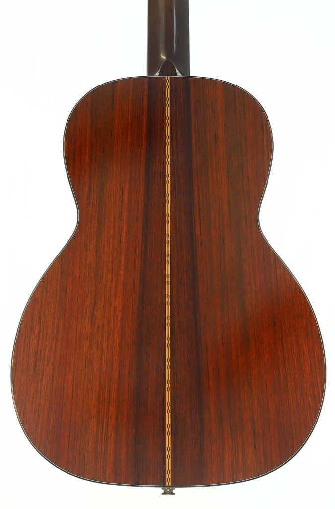 Die Rückseite der Akustikgitarre Martin 00-21 aus dem Jahr 1986, die aus poliertem dunklem Holz gefertigt ist und in der Mitte eine dekorative vertikale Einlage aufweist, ist vor einem weißen Hintergrund fotografiert. Die Rückseite der Akustikgitarre Martin 00-21 aus dem Jahr 1986, die aus poliertem dunklem Holz gefertigt ist und in der Mitte eine dekorative vertikale Einlage aufweist, ist vor einem weißen Hintergrund fotografiert.