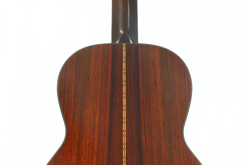 Die Rückseite der Martin 00-21 Akustikgitarre aus dem Jahr 1986, die sich durch dunkles Holz mit glänzender Lackierung und einer dekorativen gelben Einlage in der Mitte auszeichnet. Oben ist der Hals der Gitarre zu sehen. Die Rückseite der Martin 00-21 Akustikgitarre aus dem Jahr 1986, die sich durch dunkles Holz mit glänzender Lackierung und einer dekorativen gelben Einlage in der Mitte auszeichnet. Oben ist der Hals der Gitarre zu sehen.