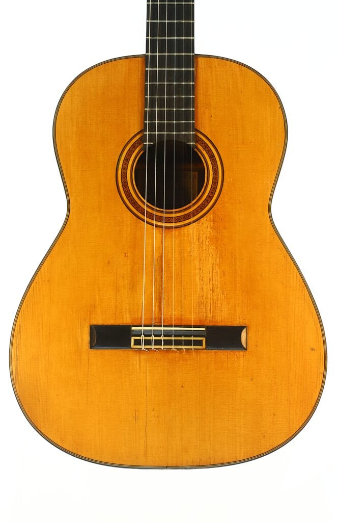 Die „Angel Alonso 1936“ Klassische Gitarre mit Holzkorpus, sichtbaren Saiten und rundem Schallloch ist vor einem weißen Hintergrund abgebildet. Die „Angel Alonso 1936“ Klassische Gitarre mit Holzkorpus, sichtbaren Saiten und rundem Schallloch ist vor einem weißen Hintergrund abgebildet.