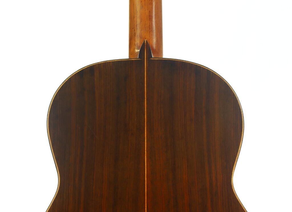 Die Rückseite der „Angel Alonso 1936 Klassische Gitarre“ ist vor weißem Hintergrund abgebildet und weist eine glänzende Oberfläche auf, die die dunkle Holzmaserung und die Mittelnaht besonders gut zur Geltung bringt. Die Rückseite der „Angel Alonso 1936 Klassische Gitarre“ ist vor weißem Hintergrund abgebildet und weist eine glänzende Oberfläche auf, die die dunkle Holzmaserung und die Mittelnaht besonders gut zur Geltung bringt.