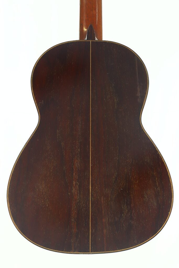 Die klassische Gitarre „Andres Martin 1966“ verfügt über einen dunklen Holzboden mit feinen Maserungen und einer schmalen, hellen Einlage, die in der Mitte entlang verläuft. Die klassische Gitarre „Andres Martin 1966“ verfügt über einen dunklen Holzboden mit feinen Maserungen und einer schmalen, hellen Einlage, die in der Mitte entlang verläuft.