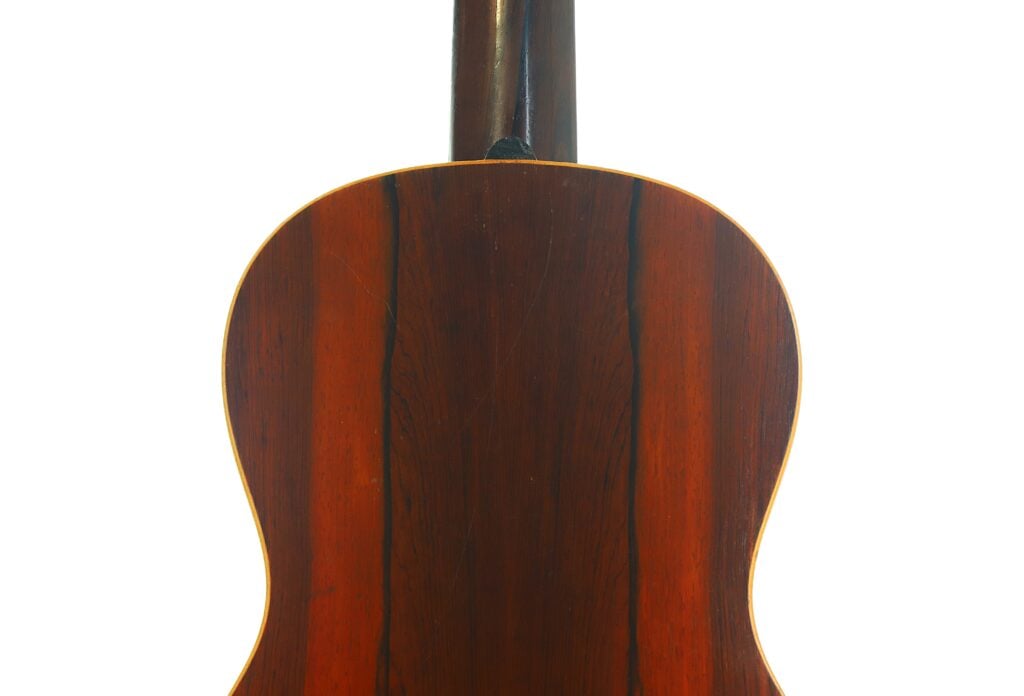Die Rückseite der James Ashborn 1850 Parlor-Akustikgitarre aus poliertem dunklem Holz mit vertikaler Maserung, fotografiert vor weißem Hintergrund. Die Rückseite der James Ashborn 1850 Parlor-Akustikgitarre aus poliertem dunklem Holz mit vertikaler Maserung, fotografiert vor weißem Hintergrund.