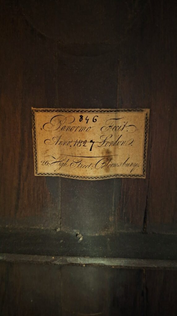 Auf einer Nahaufnahme eines alten, vergilbten Papieretiketts steht: Louis Panormo 1827 Romantikgitarre, Ann: 1827 London, 26 High Street, Shrewsbury. Das Etikett ist auf dunklem Holz angebracht. Auf einer Nahaufnahme eines alten, vergilbten Papieretiketts steht: Louis Panormo 1827 Romantikgitarre, Ann: 1827 London, 26 High Street, Shrewsbury. Das Etikett ist auf dunklem Holz angebracht.
