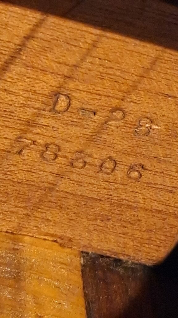 Eine Nahaufnahme der Martin D-28 1941 Pre-War Akustikgitarre, auf der die in die Holzoberfläche eingravierten Markierungen „D-23“ und „78506“ zu sehen sind. Eine Nahaufnahme der Martin D-28 1941 Pre-War Akustikgitarre, auf der die in die Holzoberfläche eingravierten Markierungen „D-23“ und „78506“ zu sehen sind.