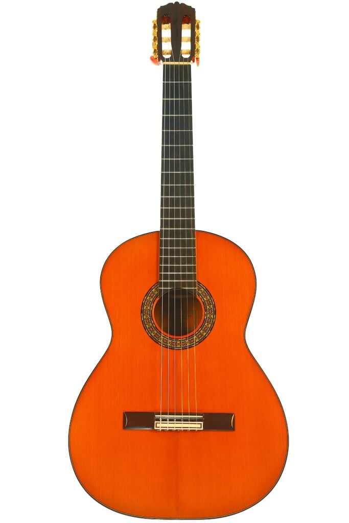 Conde Hermanos 1989 Flamenco-Gitarre mit rot-orangefarbenem Korpus, dunklem Griffbrett und einer verzierten Schalllochrosette. Conde Hermanos 1989 Flamenco-Gitarre mit rot-orangefarbenem Korpus, dunklem Griffbrett und einer verzierten Schalllochrosette.
