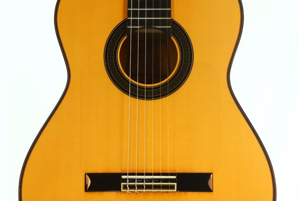 Nahaufnahme des Schalllochs, der Saiten und des Stegs einer Antonio Aparicio Master Flamenco-Gitarre. Nahaufnahme des Schalllochs, der Saiten und des Stegs einer Antonio Aparicio Master Flamenco-Gitarre.
