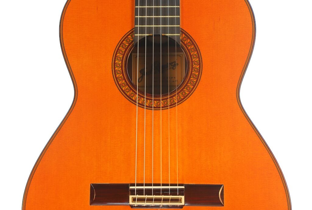 Korpus einer Jose Ramirez 1a 2019 C-650 Tradicional Klassische Gitarre mit einer dekorativen, runden Schalllochrosette und einem Steg aus dunklem Holz mit Nylonsaiten. Korpus einer Jose Ramirez 1a 2019 C-650 Tradicional Klassische Gitarre mit einer dekorativen, runden Schalllochrosette und einem Steg aus dunklem Holz mit Nylonsaiten.