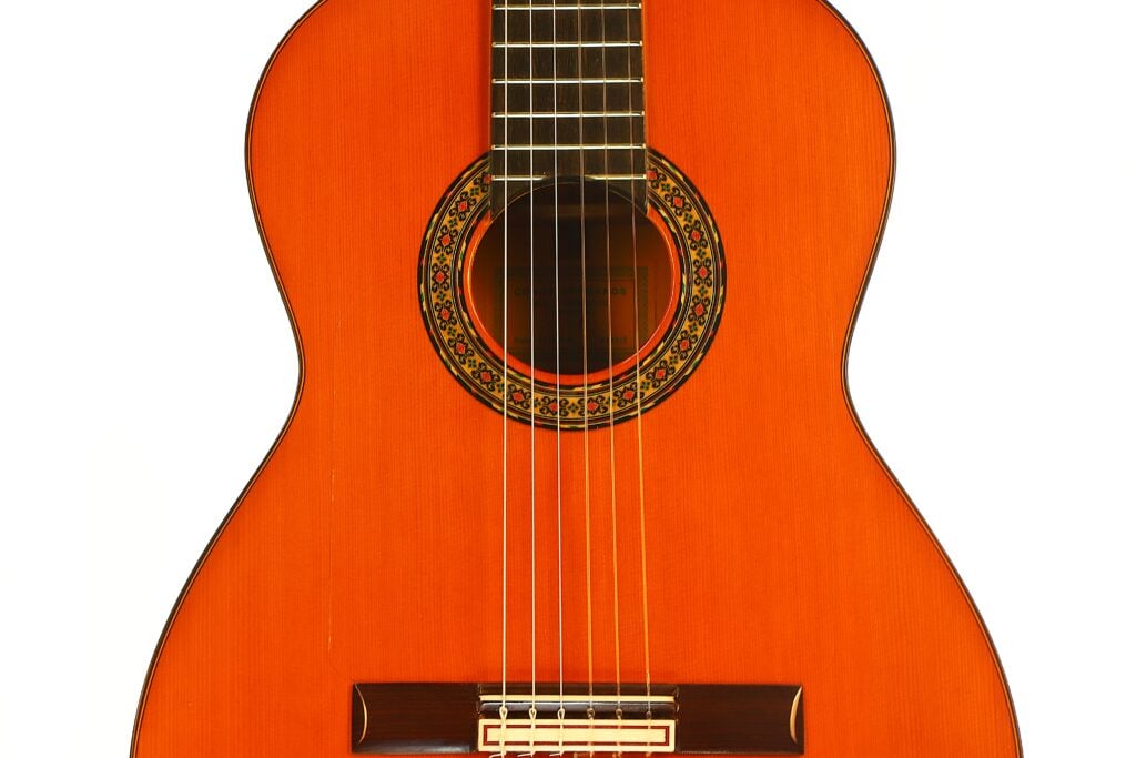Nahaufnahme des Korpus einer Flamenco-Gitarre von Conde Hermanos aus dem Jahr 1989 mit einer Rosette mit kreisförmigem Muster um das Schallloch. Nahaufnahme des Korpus einer Flamenco-Gitarre von Conde Hermanos aus dem Jahr 1989 mit einer Rosette mit kreisförmigem Muster um das Schallloch.