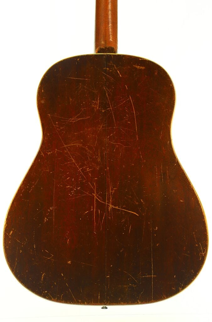 Rückansicht des Korpus einer Gibson J-45 Banner Akustikgitarre aus dem Jahr 1943 mit dunkelbrauner Lackierung und sichtbaren Kratzern auf der Oberfläche. Rückansicht des Korpus einer Gibson J-45 Banner Akustikgitarre aus dem Jahr 1943 mit dunkelbrauner Lackierung und sichtbaren Kratzern auf der Oberfläche.