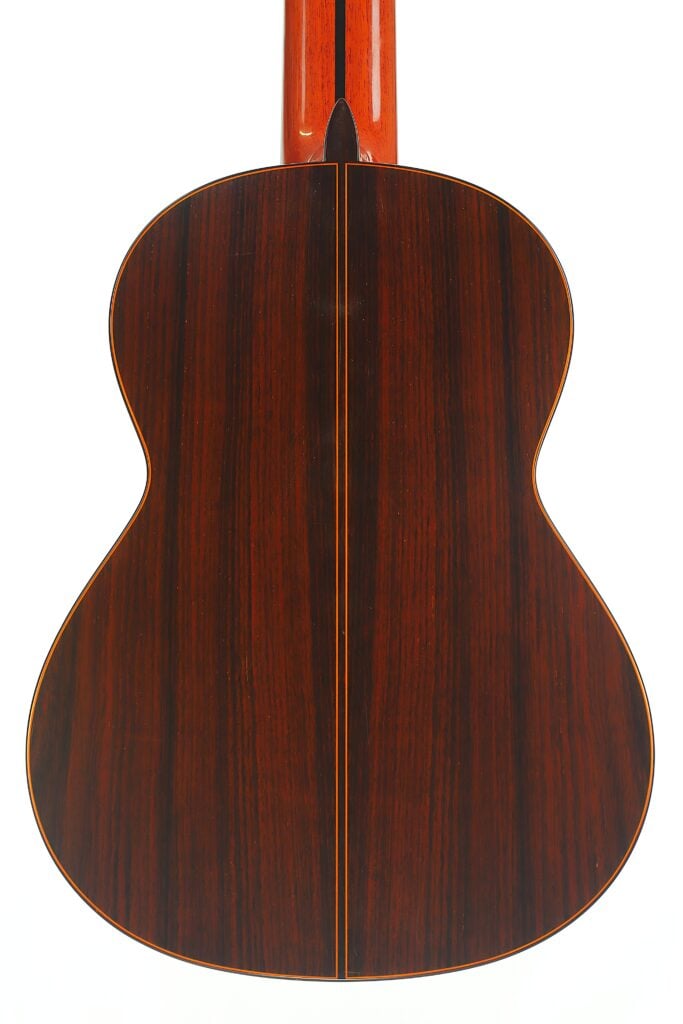 Rückansicht des Korpus der 8-saitigen klassischen Gitarre von Jose Ramirez aus dem Jahr 1984, die eine dunkle Holzmaserung mit einer vertikalen Naht in der Mitte zeigt. Rückansicht des Korpus der 8-saitigen klassischen Gitarre von Jose Ramirez aus dem Jahr 1984, die eine dunkle Holzmaserung mit einer vertikalen Naht in der Mitte zeigt.