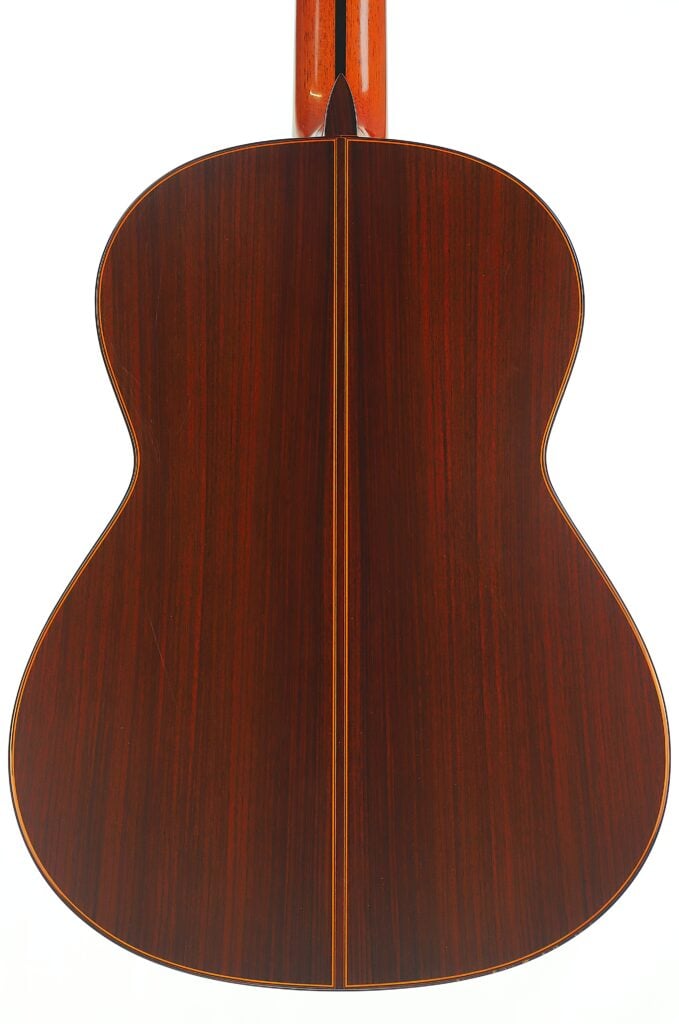 Rückansicht des Korpus der Jose Ramirez 1a 2019 C-650 Tradicional Klassische Gitarre, die eine dunkle Holzmaserung mit einem vertikalen Einlegeband in der Mitte zeigt. Rückansicht des Korpus der Jose Ramirez 1a 2019 C-650 Tradicional Klassische Gitarre, die eine dunkle Holzmaserung mit einem vertikalen Einlegeband in der Mitte zeigt.