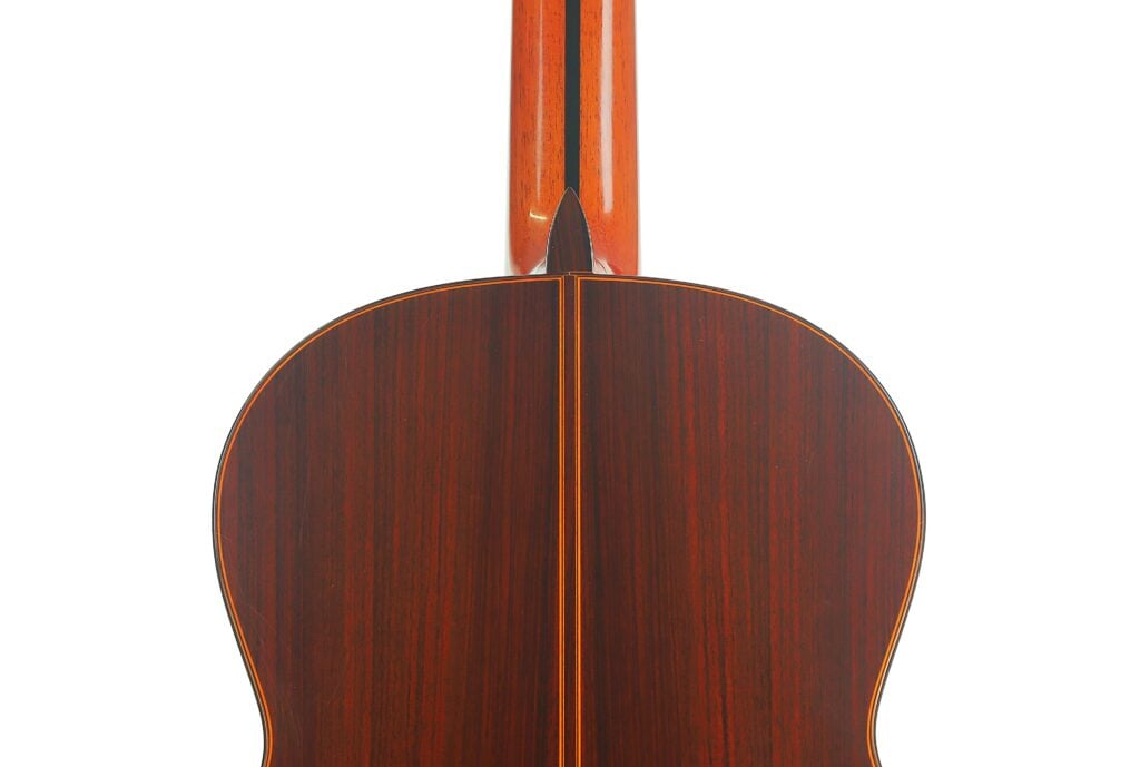 Die Rückseite einer Jose Ramirez 1a 2019 C-650 Tradicional Klassische Gitarre, auf der die dunkle Holzmaserung und der Halsfuß, an dem der Hals auf den Korpus trifft, zu sehen sind. Die Rückseite einer Jose Ramirez 1a 2019 C-650 Tradicional Klassische Gitarre, auf der die dunkle Holzmaserung und der Halsfuß, an dem der Hals auf den Korpus trifft, zu sehen sind.