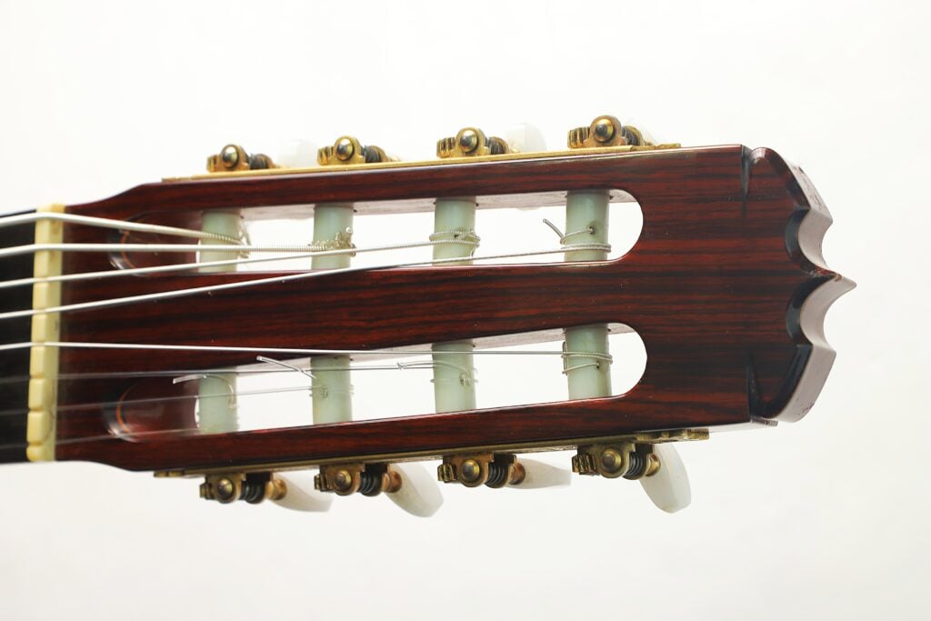Der Kopf einer 8-saitigen klassischen Gitarre von Jose Ramirez aus dem Jahr 1984 mit Stimmwirbeln aus Holz und weißen Knöpfen. Der Kopf einer 8-saitigen klassischen Gitarre von Jose Ramirez aus dem Jahr 1984 mit Stimmwirbeln aus Holz und weißen Knöpfen.