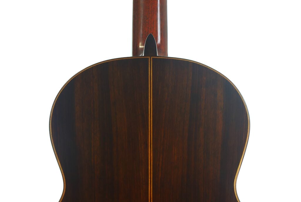 Die Rückseite einer Klassische Gitarre von Richard Howell aus dem Jahr 1980, auf der die dunkle Holzrückplatte und der Halsfuß zu sehen sind. Die Rückseite einer Klassische Gitarre von Richard Howell aus dem Jahr 1980, auf der die dunkle Holzrückplatte und der Halsfuß zu sehen sind.