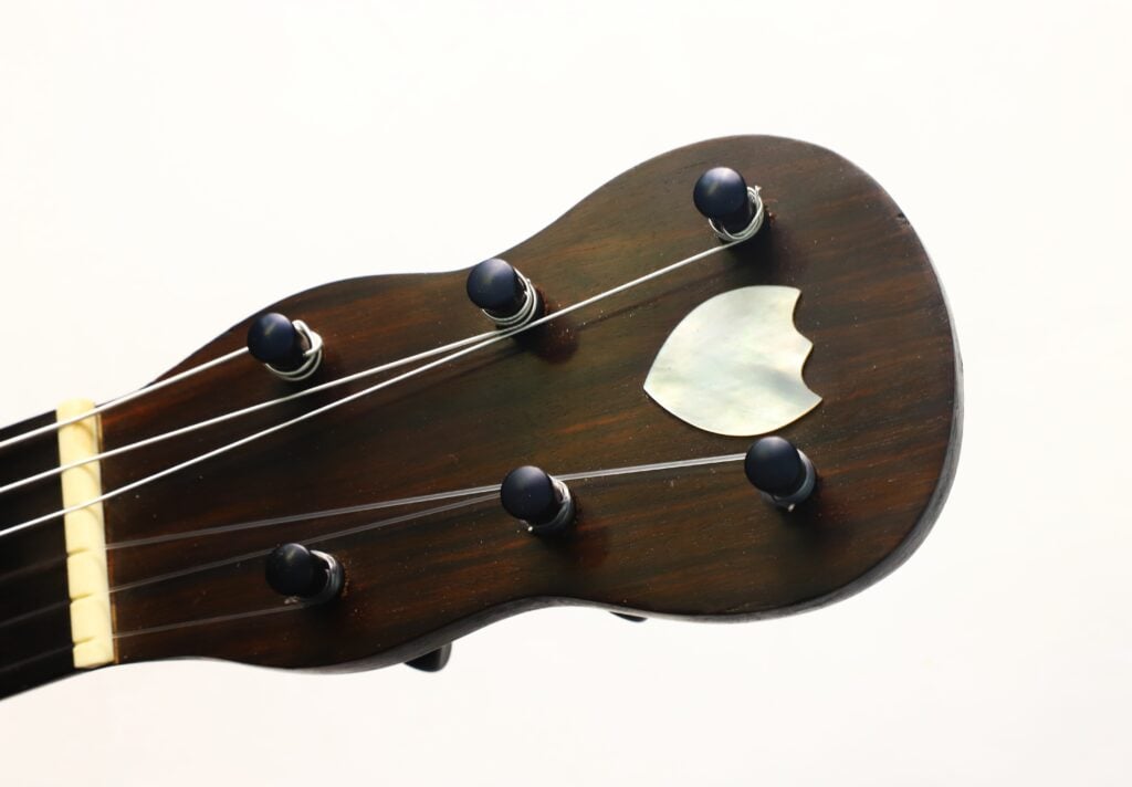 Kopfplatte aus dunklem Holz einer Carlos Gass Castañeda 1995 Modell Lacote Romantikgitarre mit Stimmwirbeln und einer kleinen Einlage aus Perlmutt. Kopfplatte aus dunklem Holz einer Carlos Gass Castañeda 1995 Modell Lacote Romantikgitarre mit Stimmwirbeln und einer kleinen Einlage aus Perlmutt.