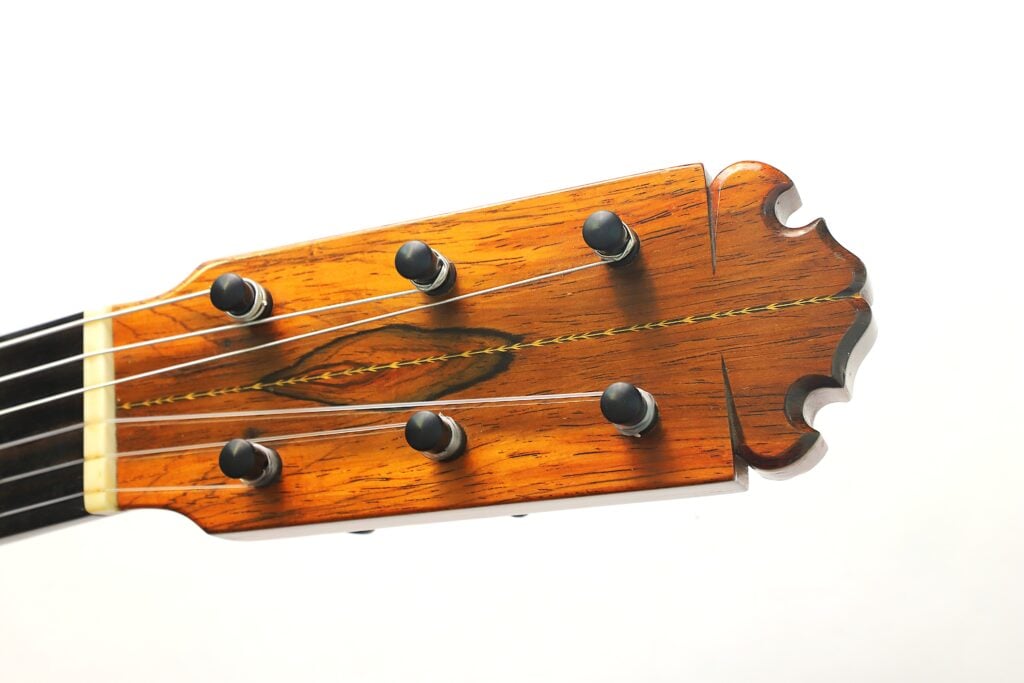 Holzkopf einer Manuel Contreras 1a Flamenco-Gitarre aus dem Jahr 1977 mit sechs Stimmwirbeln, Einlagen aus dunklem Holz und einer kunstvoll geschnitzten Oberseite. Holzkopf einer Manuel Contreras 1a Flamenco-Gitarre aus dem Jahr 1977 mit sechs Stimmwirbeln, Einlagen aus dunklem Holz und einer kunstvoll geschnitzten Oberseite.