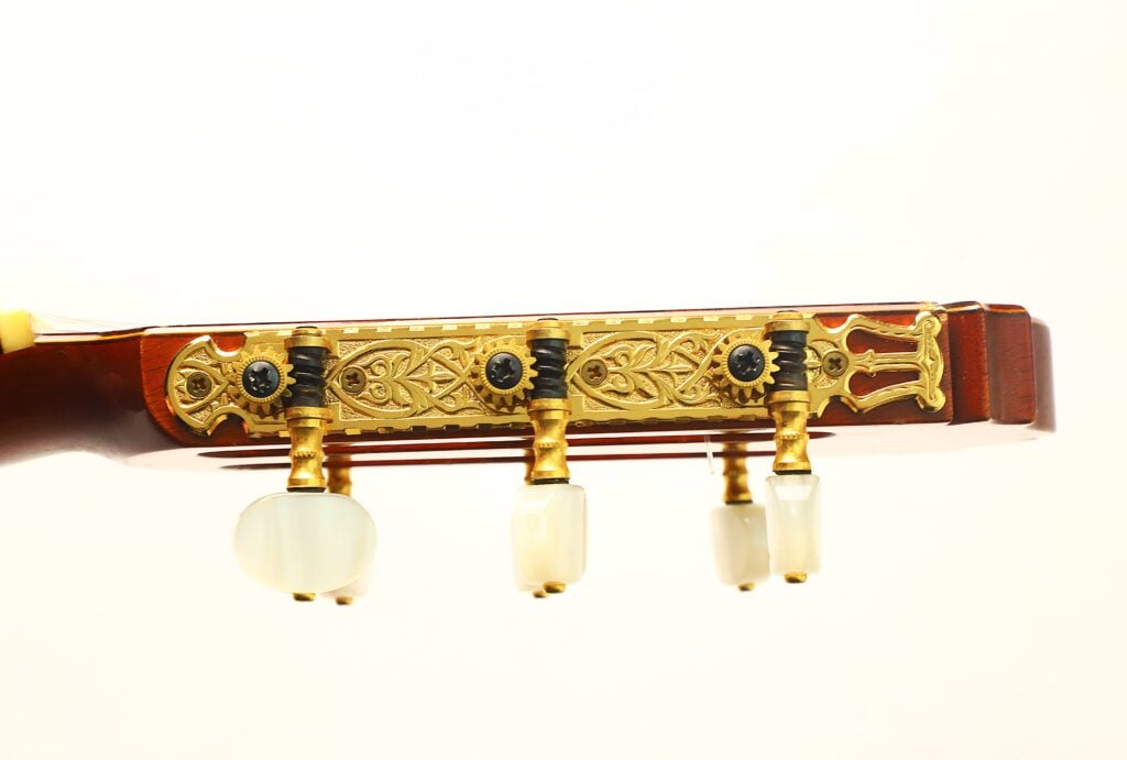 Nahaufnahme des Kopfes einer Masaru Kohno 1990 Professional J Klassische Gitarre mit kunstvoll verzierten goldenen Stimmmechaniken und Perlmutt-Stimmknöpfen. Nahaufnahme des Kopfes einer Masaru Kohno 1990 Professional J Klassische Gitarre mit kunstvoll verzierten goldenen Stimmmechaniken und Perlmutt-Stimmknöpfen.