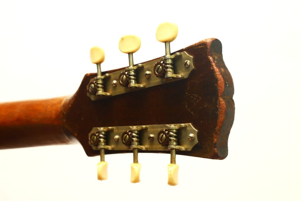 Rückseite einer Gibson J-45 Banner Akustikgitarre aus dem Jahr 1943 mit Kopfplatte und sechs offenen Stimmwirbeln. Rückseite einer Gibson J-45 Banner Akustikgitarre aus dem Jahr 1943 mit Kopfplatte und sechs offenen Stimmwirbeln.