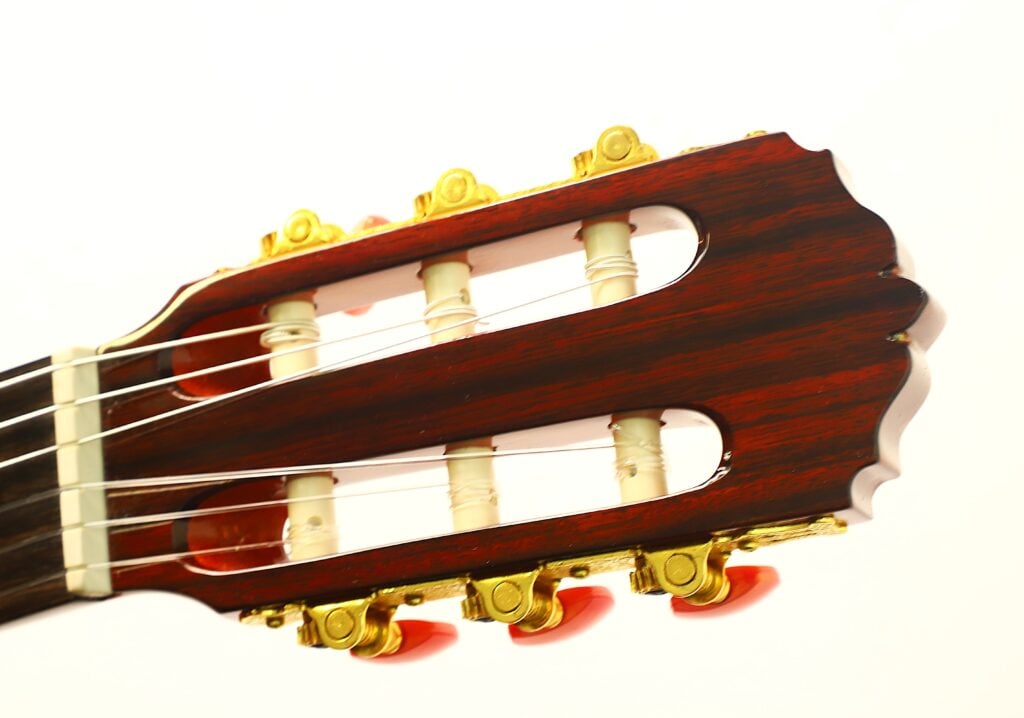Kopfplatte einer Flamenco-Gitarre von Conde Hermanos aus dem Jahr 1989 mit goldenen Stimmmechaniken und roten Einstellknöpfen. Kopfplatte einer Flamenco-Gitarre von Conde Hermanos aus dem Jahr 1989 mit goldenen Stimmmechaniken und roten Einstellknöpfen.