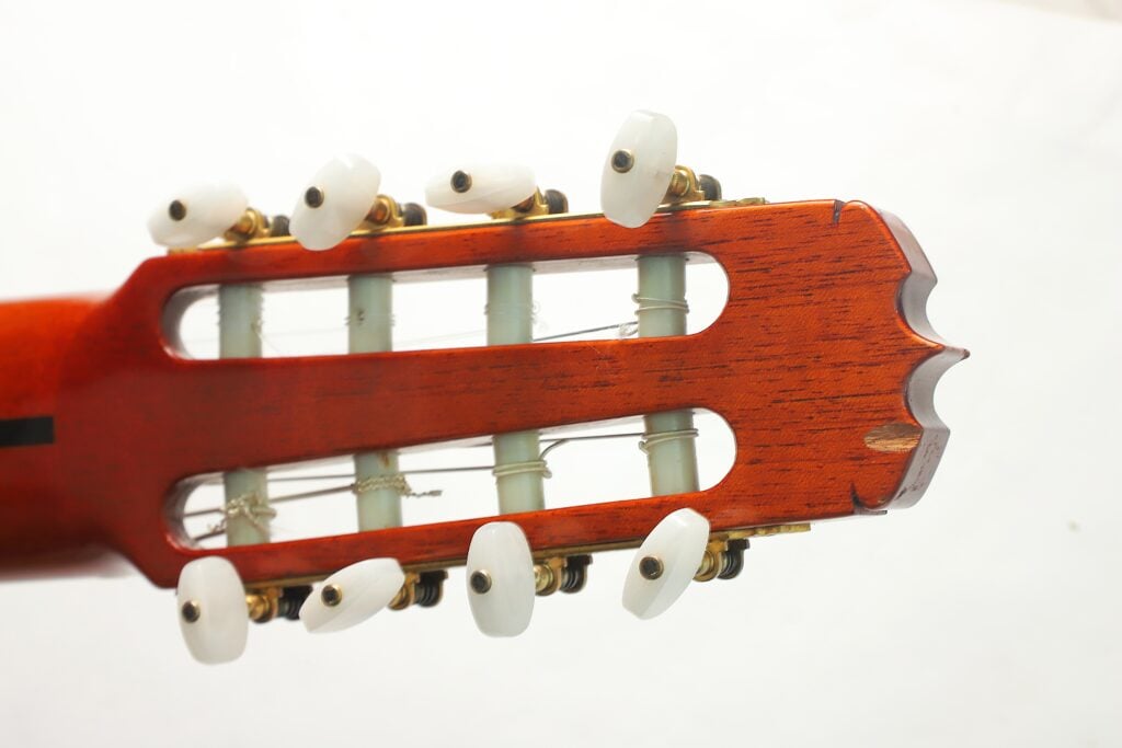 Kopfplatte einer 8-saitigen klassischen Gitarre von Jose Ramirez aus dem Jahr 1984 mit weißen Stimmwirbeln und Nylonsaiten. Kopfplatte einer 8-saitigen klassischen Gitarre von Jose Ramirez aus dem Jahr 1984 mit weißen Stimmwirbeln und Nylonsaiten.