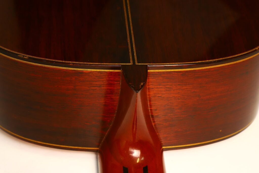 Nahaufnahme der Halsverbindung aus dunklem Holz und des umgebenden Korpus einer Masaru Kohno 1990 Professional J Klassischen Gitarre. Nahaufnahme der Halsverbindung aus dunklem Holz und des umgebenden Korpus einer Masaru Kohno 1990 Professional J Klassischen Gitarre.