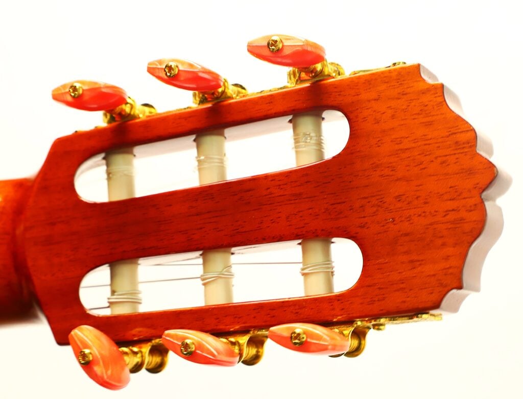 Nahaufnahme des Kopfes einer Flamenco-Gitarre von Conde Hermanos aus dem Jahr 1989 mit sechs Stimmwirbeln und bernsteinfarbenen Knöpfen. Nahaufnahme des Kopfes einer Flamenco-Gitarre von Conde Hermanos aus dem Jahr 1989 mit sechs Stimmwirbeln und bernsteinfarbenen Knöpfen.