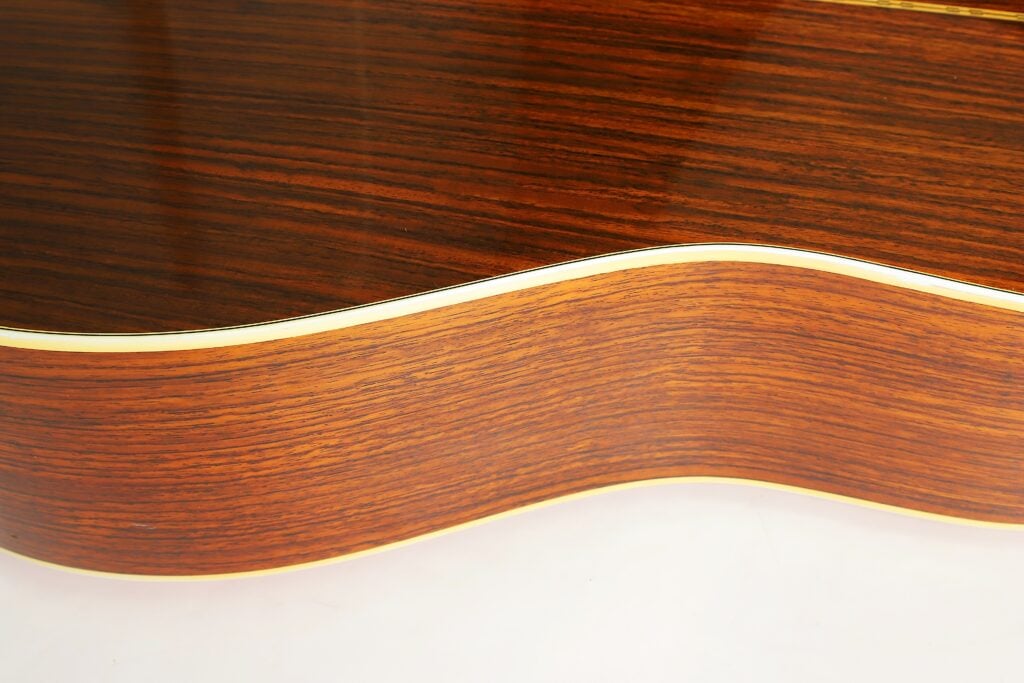 Nahaufnahme der Seite und Oberseite des Korpus einer Martin D-28 Akustikgitarre aus dem Jahr 1975, auf der die Holzmaserung zu sehen ist. Nahaufnahme der Seite und Oberseite des Korpus einer Martin D-28 Akustikgitarre aus dem Jahr 1975, auf der die Holzmaserung zu sehen ist.