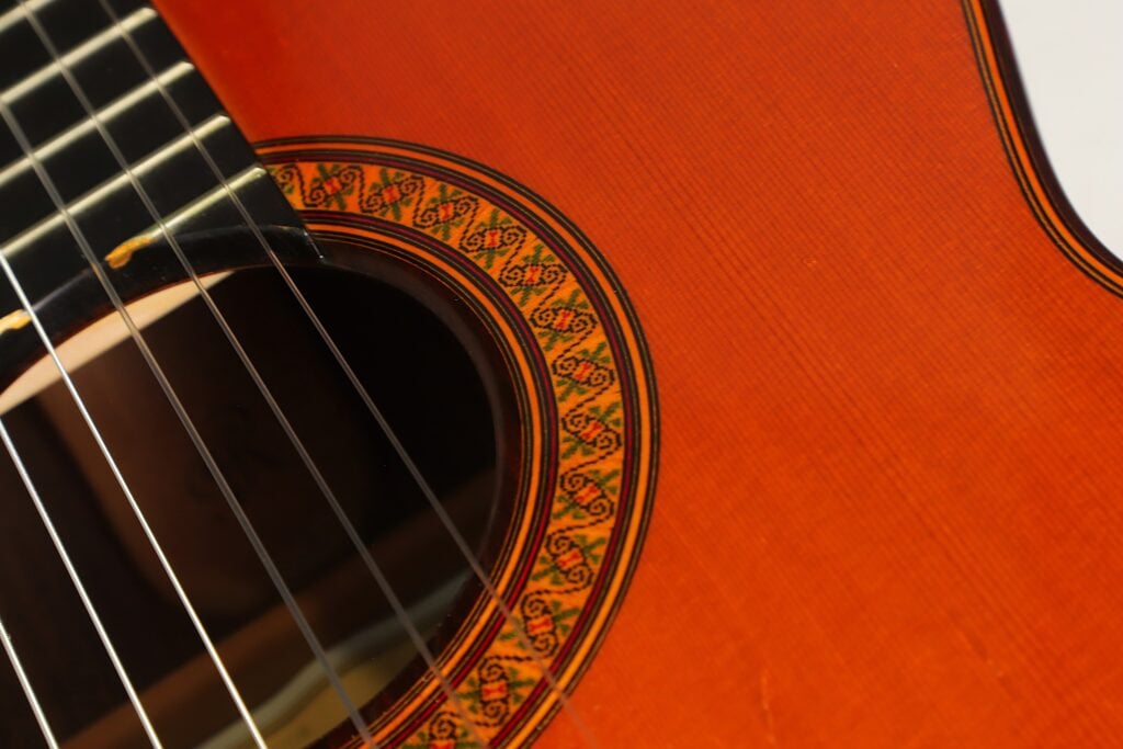 Nahaufnahme einer Jose Ramirez 1a 2019 C-650 Tradicional Klassische Gitarre mit Blick auf das Schallloch, die Saiten und eine detailreiche Rosettenintarsie. Nahaufnahme einer Jose Ramirez 1a 2019 C-650 Tradicional Klassische Gitarre mit Blick auf das Schallloch, die Saiten und eine detailreiche Rosettenintarsie.