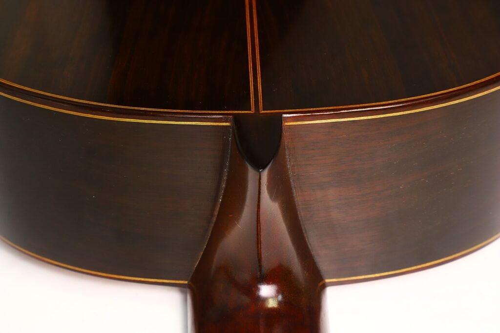 Nahaufnahme des Halsfußes und des Sattelstücks der Klassische Gitarre von Richard Howell aus dem Jahr 1980 aus dunklem Holz. Nahaufnahme des Halsfußes und des Sattelstücks der Klassische Gitarre von Richard Howell aus dem Jahr 1980 aus dunklem Holz.
