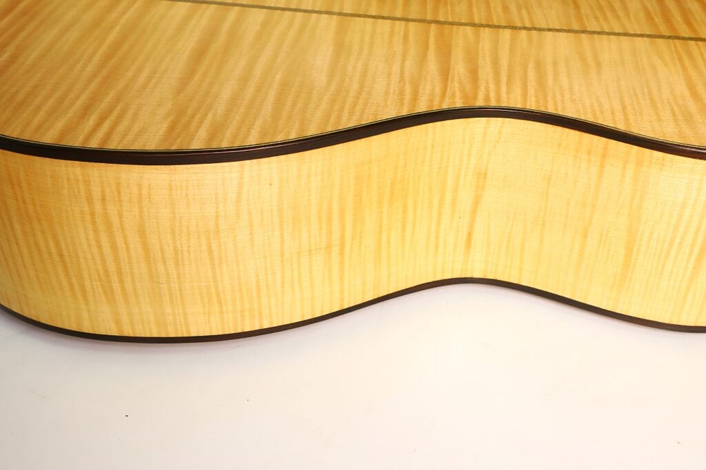 Nahaufnahme eines hellen Holzkörpers mit welliger Maserung bei einer Modell Lacote Romantikgitarre von Carlos Gass Castañeda aus dem Jahr 1995. Nahaufnahme eines hellen Holzkörpers mit welliger Maserung bei einer Modell Lacote Romantikgitarre von Carlos Gass Castañeda aus dem Jahr 1995.