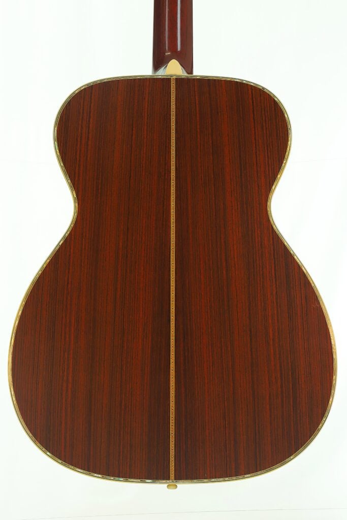 Rückansicht einer Martin SOM-45 Akustikgitarre aus dem Jahr 1977, die die Maserung des zweiteiligen Bodens mit einem dekorativen Mittelstreifen und cremefarbener Einfassung zeigt. Rückansicht einer Martin SOM-45 Akustikgitarre aus dem Jahr 1977, die die Maserung des zweiteiligen Bodens mit einem dekorativen Mittelstreifen und cremefarbener Einfassung zeigt.