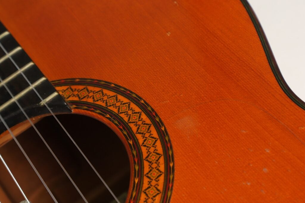 Nahaufnahme des Korpus einer Flamenco-Gitarre von Manuel Contreras, Modell 1a, Baujahr 1977, mit Blick auf das Schallloch, die kunstvoll verzierte runde Rosette und die Holzmaserung. Nahaufnahme des Korpus einer Flamenco-Gitarre von Manuel Contreras, Modell 1a, Baujahr 1977, mit Blick auf das Schallloch, die kunstvoll verzierte runde Rosette und die Holzmaserung.