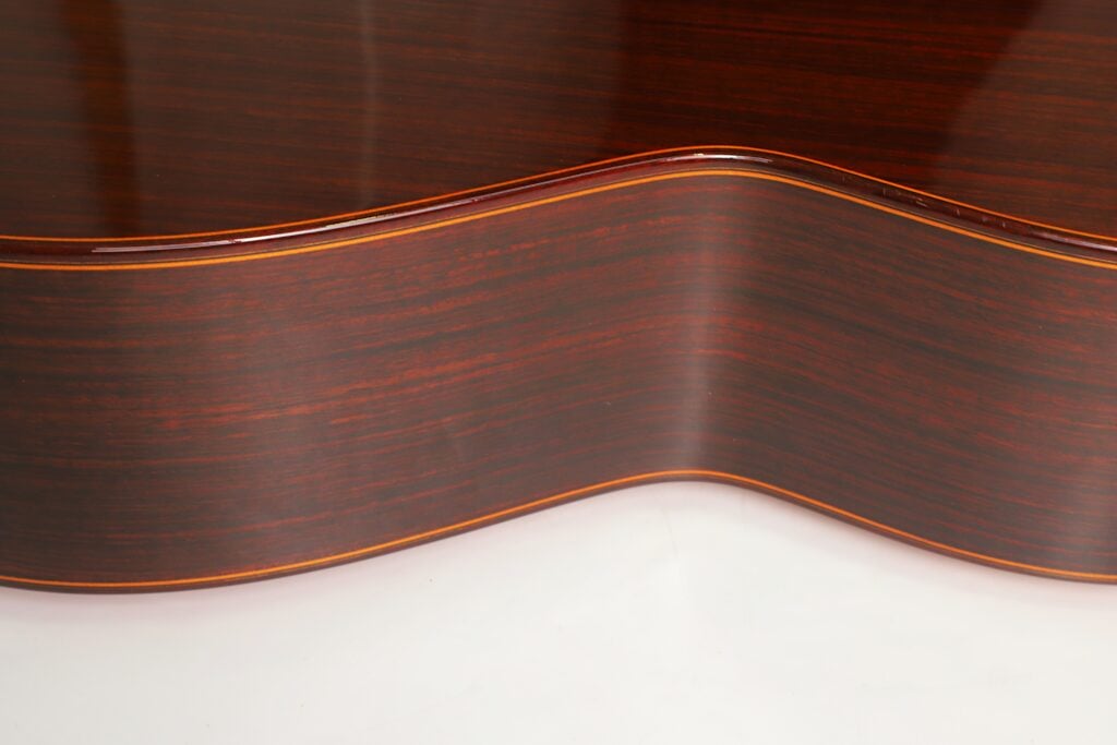 Nahaufnahme des Korpus aus dunklem Holz und der geschwungenen Taille einer Jose Ramirez 1a 2019 C-650 Tradicional Klassische Gitarre. Nahaufnahme des Korpus aus dunklem Holz und der geschwungenen Taille einer Jose Ramirez 1a 2019 C-650 Tradicional Klassische Gitarre.