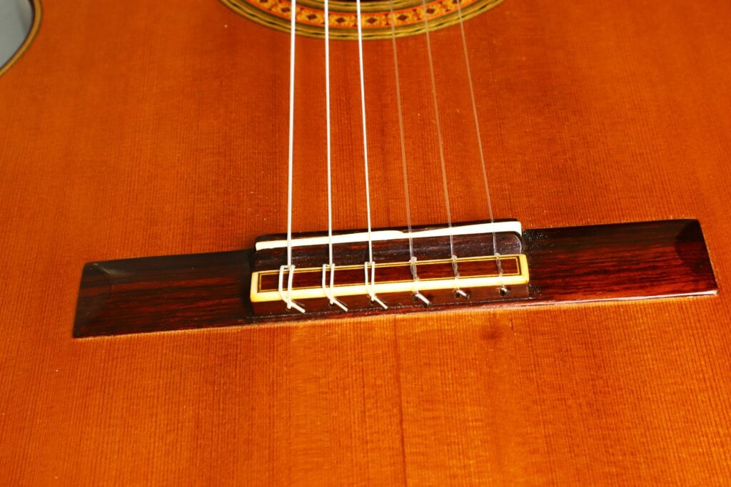 Nahaufnahme des Stegs und der Saiten einer klassischen Gitarre von Richard Howell aus dem Jahr 1980. Nahaufnahme des Stegs und der Saiten einer klassischen Gitarre von Richard Howell aus dem Jahr 1980.