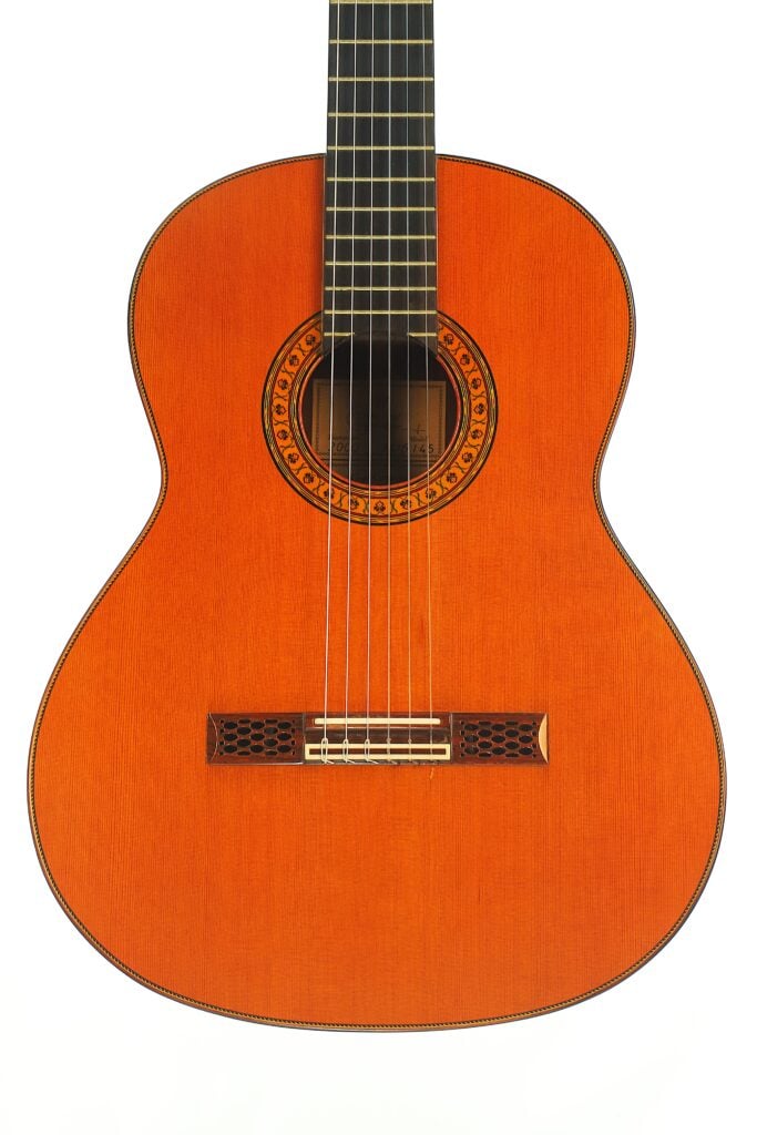 Klassische Gitarre Hopf Gran Concertio 2000 mit Holzkorpus, einer Rosette mit kreisförmigem Muster am Schallloch und einem Steg mit dekorativen Ausschnitten. Klassische Gitarre Hopf Gran Concertio 2000 mit Holzkorpus, einer Rosette mit kreisförmigem Muster am Schallloch und einem Steg mit dekorativen Ausschnitten.