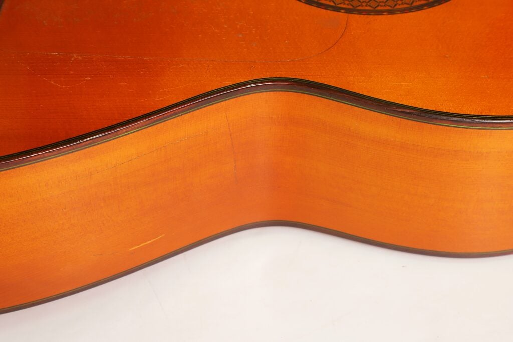 Nahaufnahme des Holzkörpers einer Flamenco-Gitarre vom Typ Manuel Contreras 1a 1977, die die Rundungen der Taille und der Decke zeigt. Nahaufnahme des Holzkörpers einer Flamenco-Gitarre vom Typ Manuel Contreras 1a 1977, die die Rundungen der Taille und der Decke zeigt.